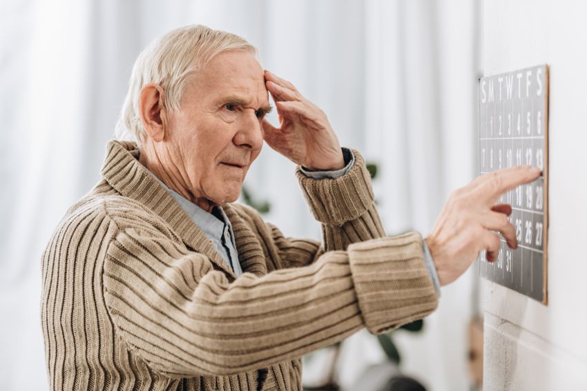 Starszy pan chory na Alzheimera sprawdza datę w kalendarzu