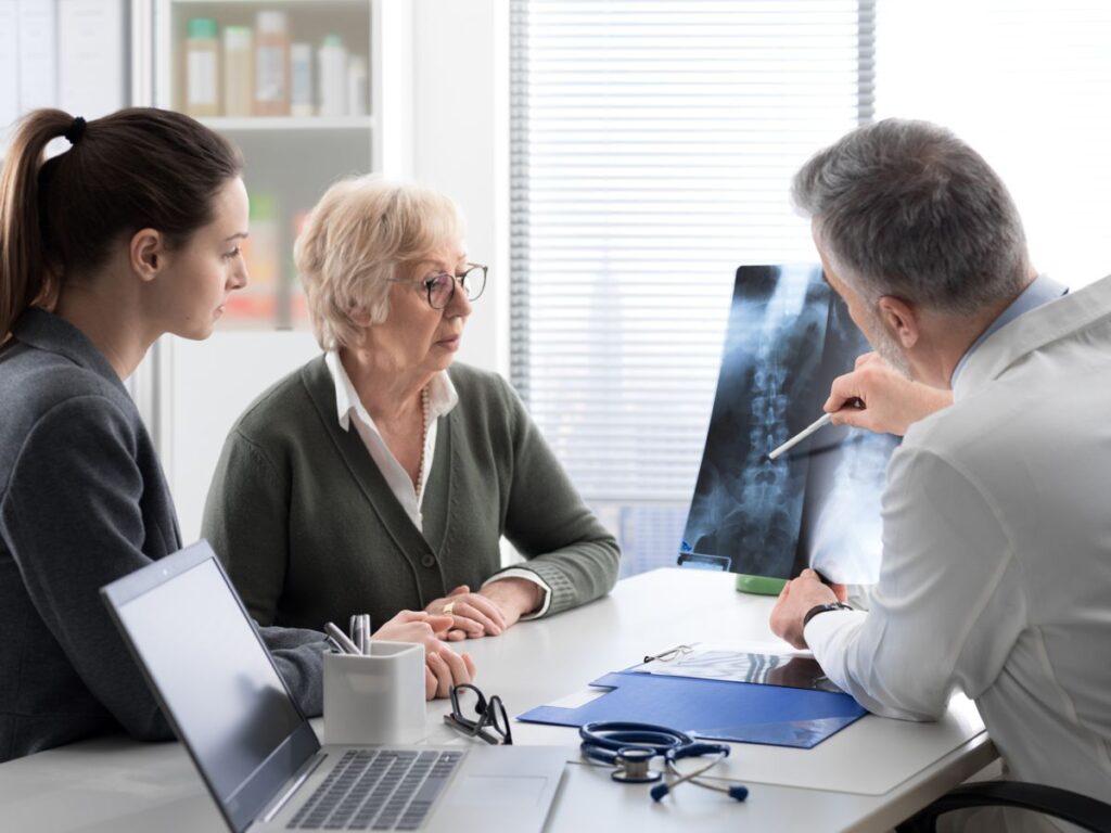 Starsza osoba chora na osteoporozę w lekarza ogląda zdjęcie RTG kręgosłupa
